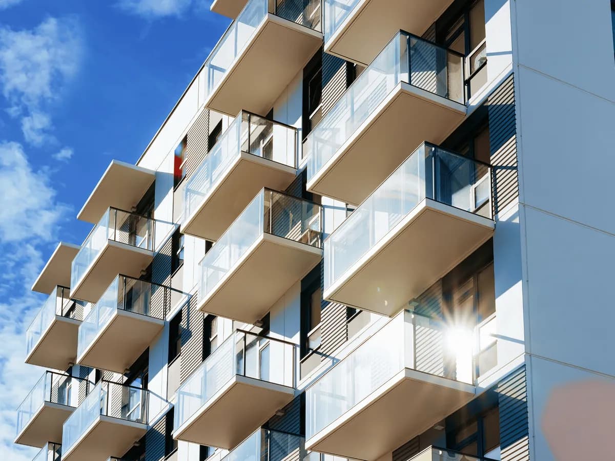 Helle und gepflegte Wohnanlage mit modernen Glasbalkonen bei blauem Himmel